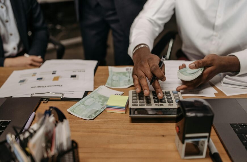 INICIO Professional setting with people handling cash and calculations using a calculator at a desk.