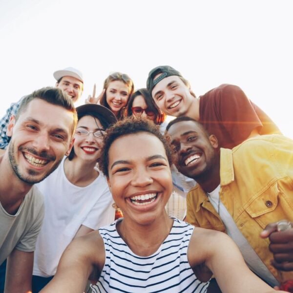 Comunidad A diverse group of friends taking a joyful selfie outdoors during sunset.