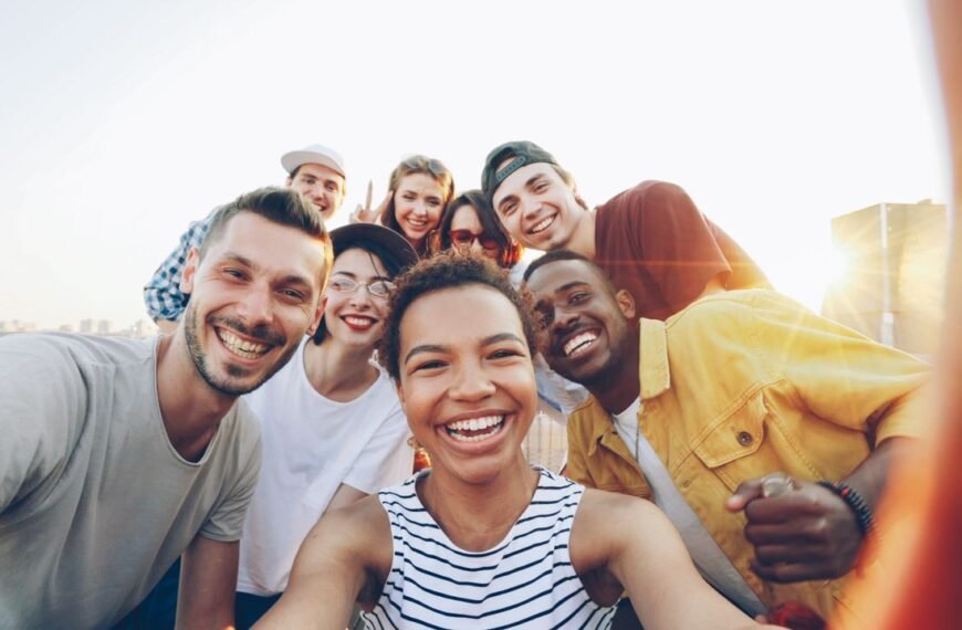 INICIO A diverse group of friends taking a joyful selfie outdoors during sunset.